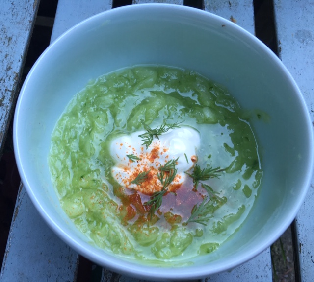 Salad bowl filled with jade green cucumber, topped with sour cream, dill and paprika